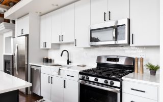 White painted kitchen cabinetry with black hardware, stainless steel appliances, and white subway tile backsplash. how long does cabinet paint take to cure