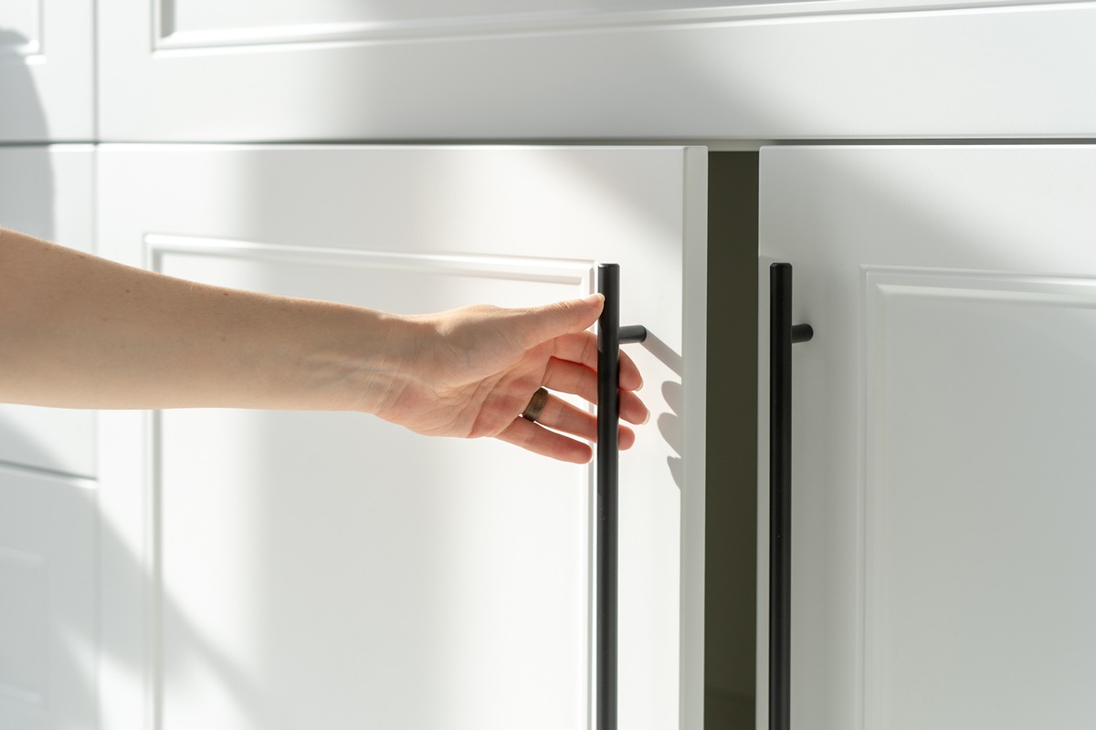 Woman’s hand holding on handle of kitchen cabinet